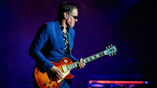 Joe Bonamassa playing an electric guitar onstage under blue and purple lighting, appearing at the F.M. Kirby Center in Wilkes-Barre, PA.