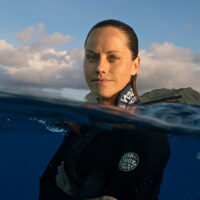 Dr. Jess Cramp partially submerged in ocean water during shark research, featured at the F.M. Kirby Center in Wilkes-Barre, PA.