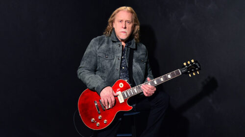 Warren Haynes seated with an electric guitar against a dark background, performing with the Warren Haynes Band at the F.M. Kirby Center in Wilkes-Barre, PA.
