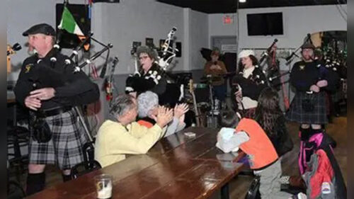 The Parade Week Pub Crawl at Downtown Pittston, PA, takes place on February 28 and features bagpipers performing inside a crowded pub while guests clap and watch from long wooden tables