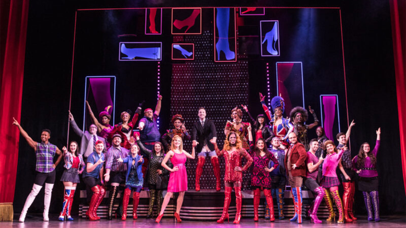 Full cast of Kinky Boots in colorful costumes and red boots in a promotion image for their upcoming Broadway Theatre League performance at the Scranton Cultural Center in Scranton, PA.