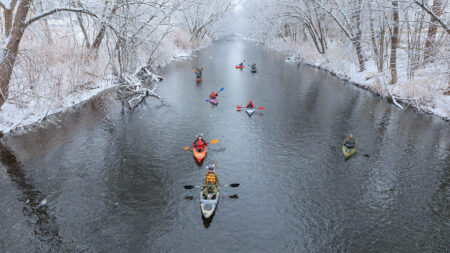 A group of kayakers make their way down snowy Lackawanna River during Shiverfest in Scranton, PA.