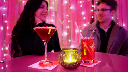 Two cocktails and a candle on a table in front of a couple at the Blush Lounge pop-up bar at Mohegan Pennsylvania casino in Wilkes-Barre, PA.