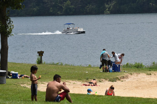 Families picnick in the grass near the sandy beach at Beltzville State Park in Lehighton, PA.