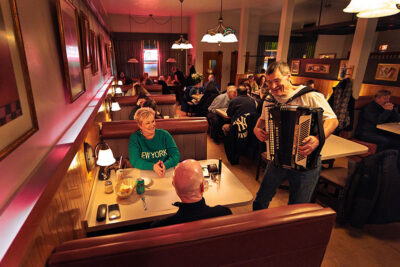 A man plays an accordion beside seated diners inside a restaurant during Celebrate Music in Pittston, PA.