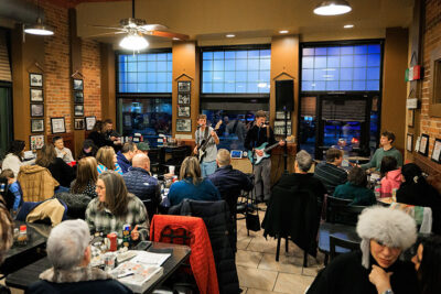 A band performs on stage inside a restaurant as seated diners watch during Celebrate Music in Pittston, PA.