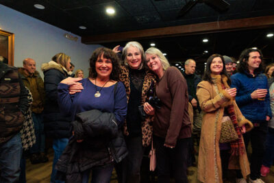 Three women pose together inside a crowded venue during Celebrate Music in Pittston, PA.