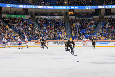 Hockey players chase the puck on ice at the WIlkes-Barre/Scranton Penguins game in Wilkes-Barre, PA.