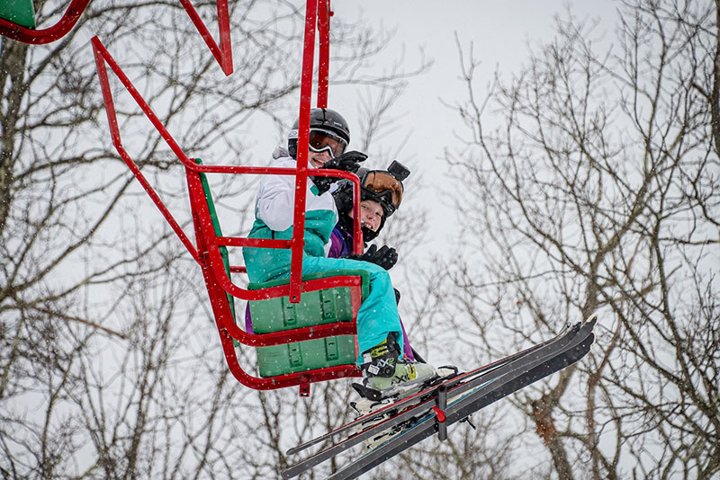 Two young girls wearing skis ride a red chair lift at Ski Big Bear in Lackawaxen, PA. 