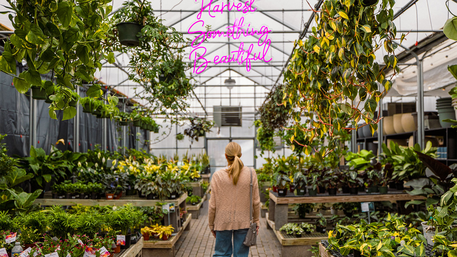 Woman walking through the greenhouse at Corky's Garden Path, with a 