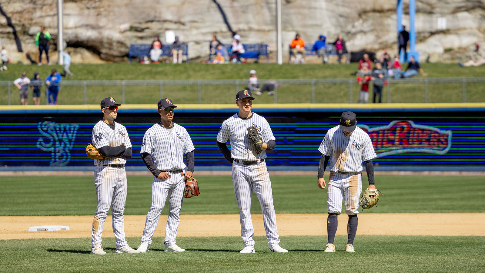 Four RailRiders baseball players standing on the field mid-game on opening day at PNC Field in Moosic, PA.