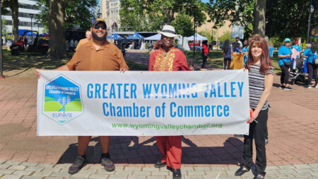 A gropu of volunteers holds up a Greater Wyoming Valley Chamber of Commerce sign on Public Square in Wilkes-Barre, PA.