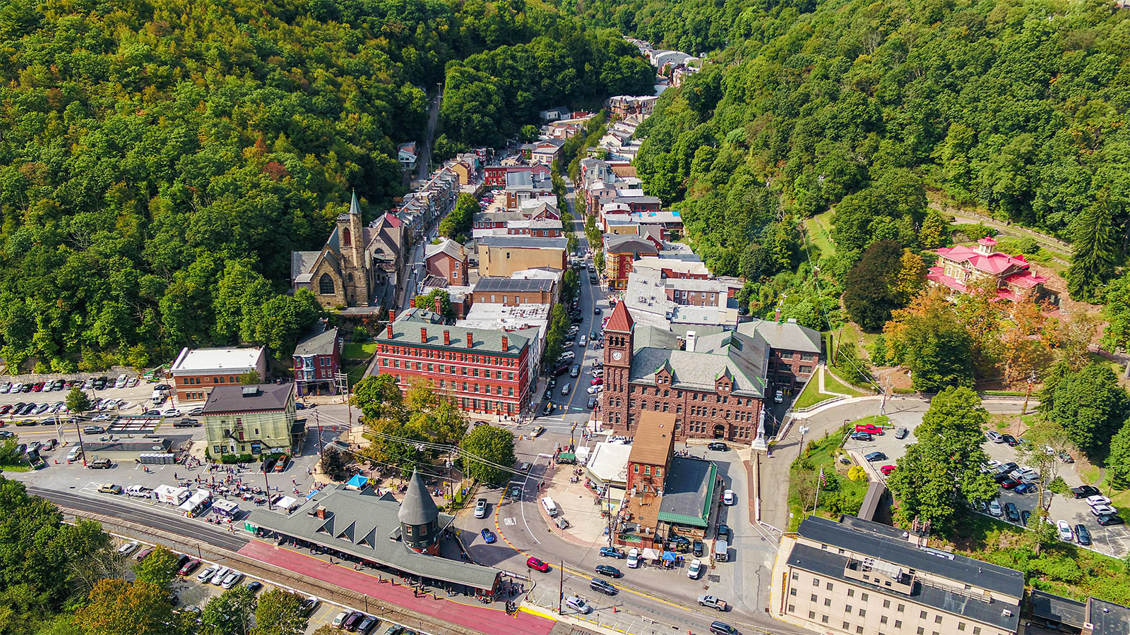 An aerial view of Jim Thorpe, Pennsylvania, nestled in a valley with St. Mark's Episcopal Church and other buildings visible among the foliage.