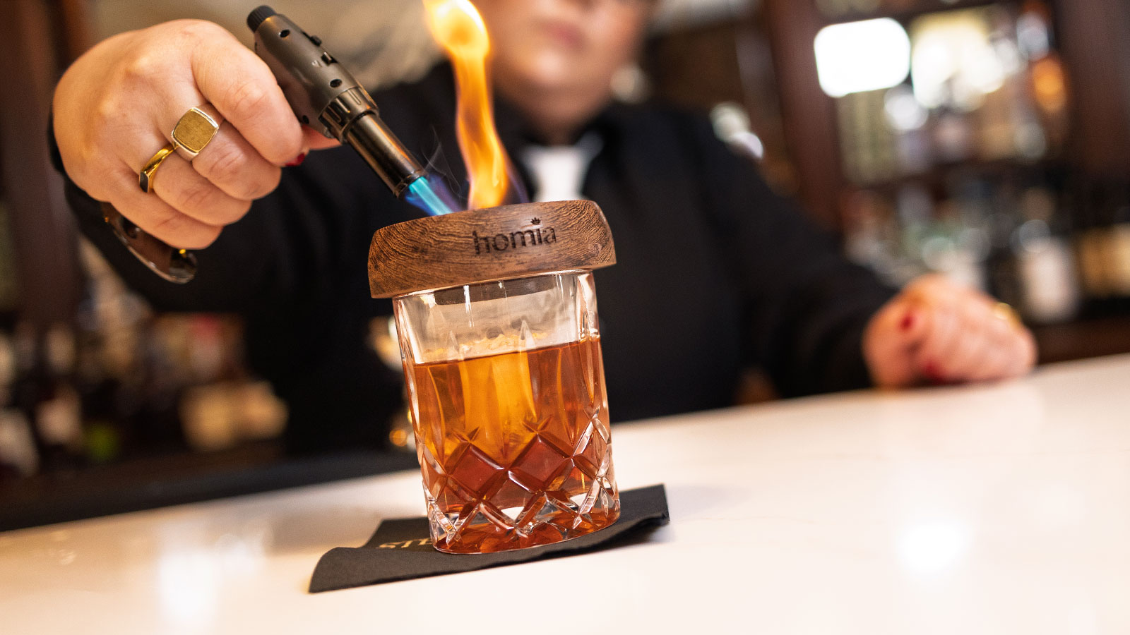 Bartender using a hand torch to smoke a cocktail behind the bar at The Stegmaier in Wilkes-Barre, PA.