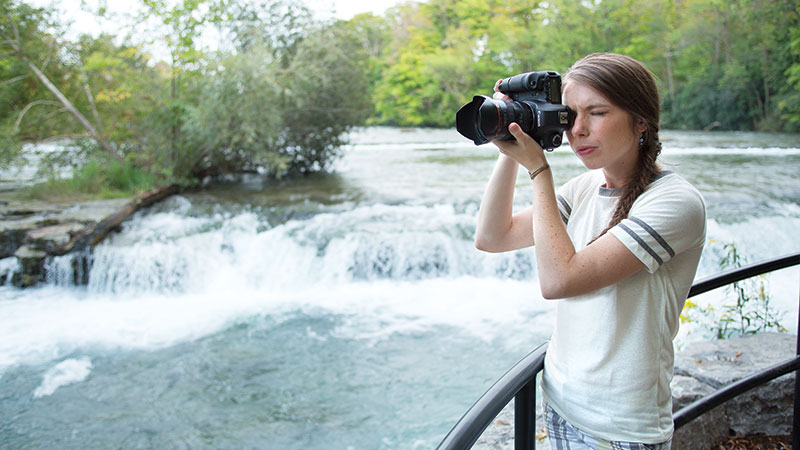 A woman taking a photo of her sites while exploring Goat Island at Niagara Falls.