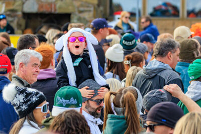 A boy with pink sunglasses and a white winter hat sits on his dad's shoulders at Mountainfest at Montage Mountain in Moosic, PA.