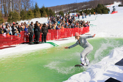 A girl snowboards across the pond at Mountainfest at Montage Mountain in Moosic, PA.