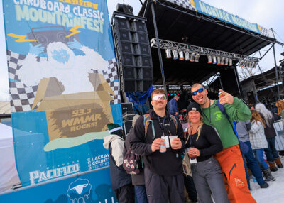 A group of three smile for the camera while standing in front of the stage at Mountainfest at Montage Mountain in Moosic, PA.