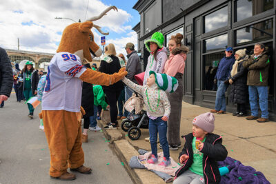 A deer mascot gives a high five to a little girl in an green and white Dr. Seuss hat during the St. Patrick's Day parade in Scranton, PA.