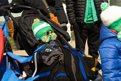 A baby completely covered in warm clothes sits in a stroller watching the parade during the St. Patrick's Day parade in Scranton, PA.