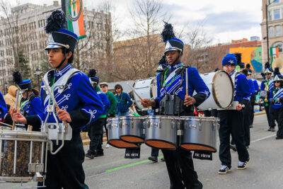 A boy from a school band plays percussion while marching down the street in Scranton's St. Patrick's Day parade.