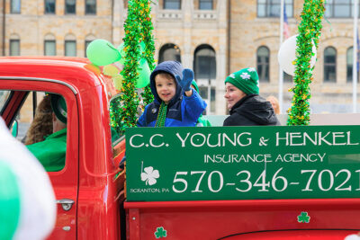 A boy in the back of an old pickup truck waves to people on the street in Scranton's St. Patrick's Day parade.