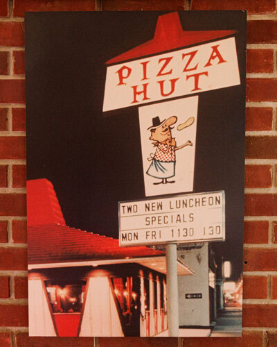 A image of the original Pizza Hut hangs on a brick wall inside Pizza Hut Classic in Tunkhannock, PA.
