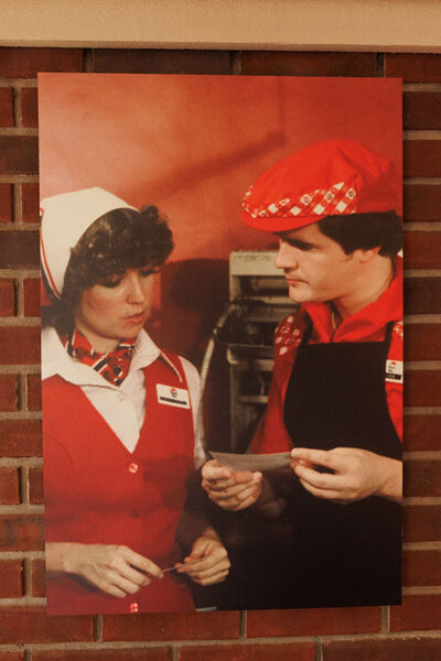 An old image hangs on a brick wall of a man and woman from the 80's working at Pizza Hut at Pizza Hut Classic in Tunkhannock, PA.
