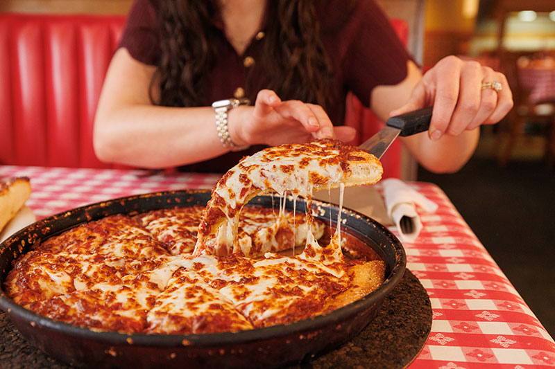 A woman takes a slice of pizza while it drips cheese at Pizza Hut Classic in Tunkhannock, PA.