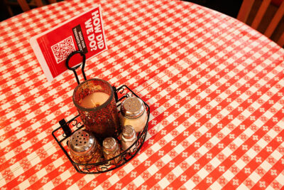 Pizza condiments sit on a red and white checkered tablecloth at Pizza Hut Classic in Tunkhannock, PA.
