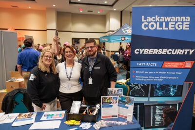 Three representatives from Lackawanna College smile for a photo during a career exploration event at the Mohegan Pennsylvania Convention Center in Wilkes-Barre, PA.