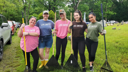 Volunteers for the United Way Day of Caring post with rakes.